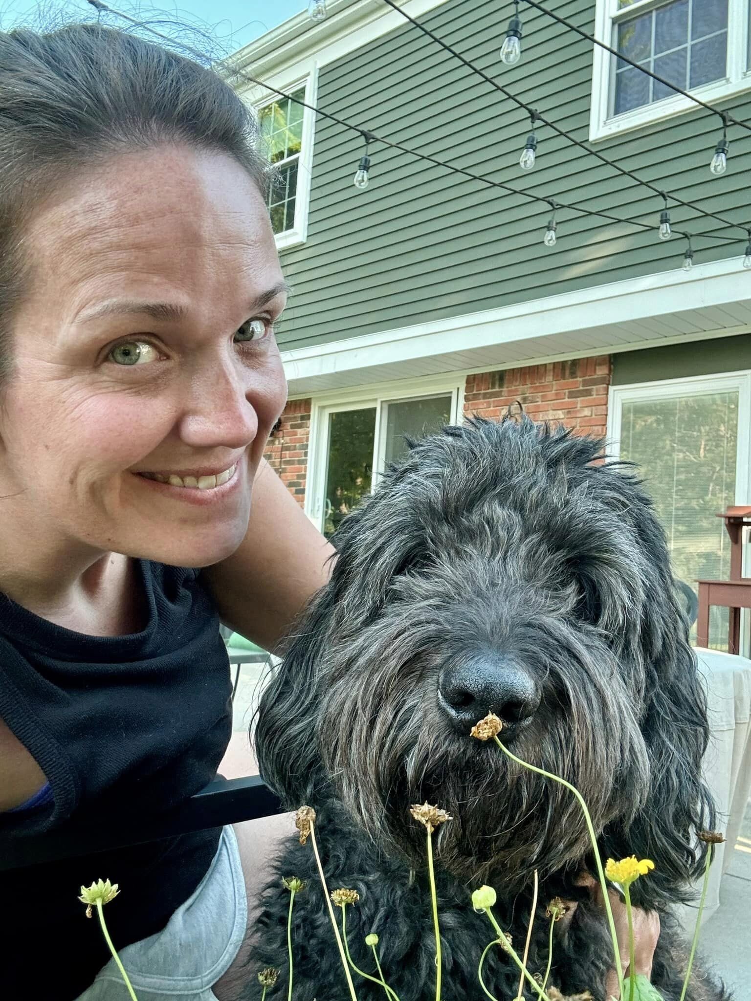 Testimonial photo of Amber taking a selfie with her black Newfypoo for Dogology University