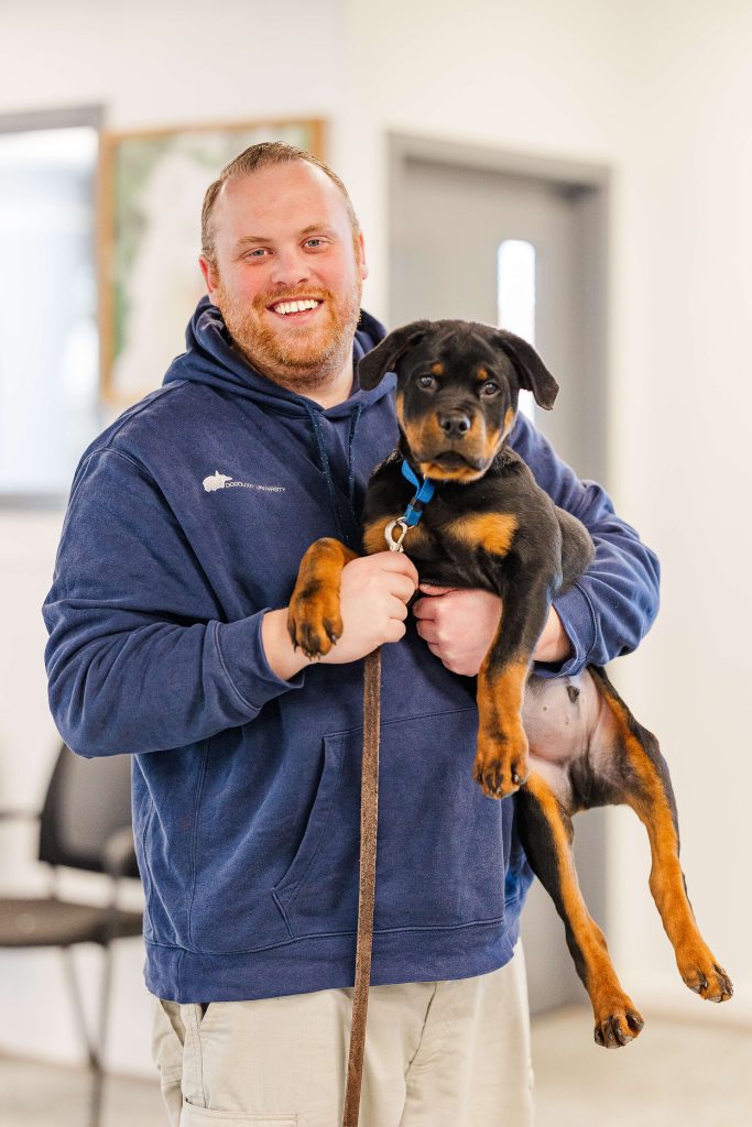 Matthew Lamarand, founder of Dogology University, holding a smiling Rottweiler puppy during a training session