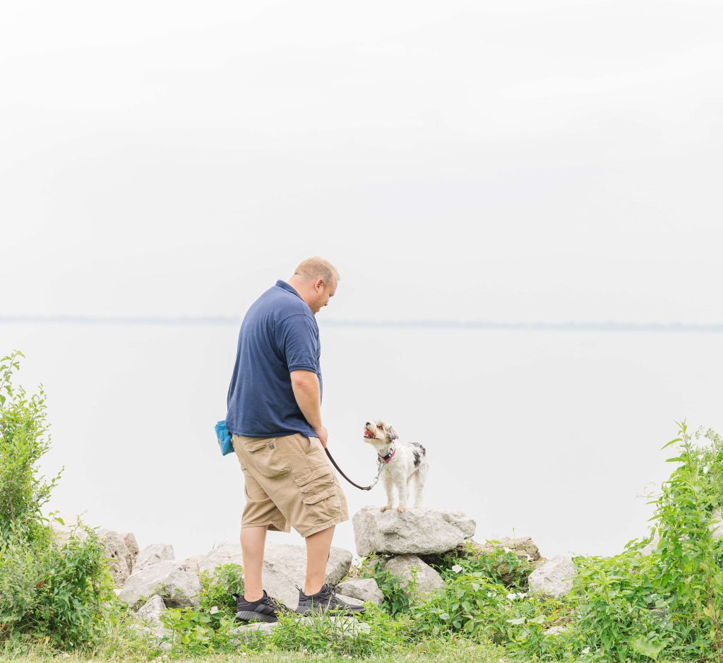 Matthew Lamarand, founder of Dogology University, training a small terrier on a large rock at Sterling State Park as part of the mobile day training program