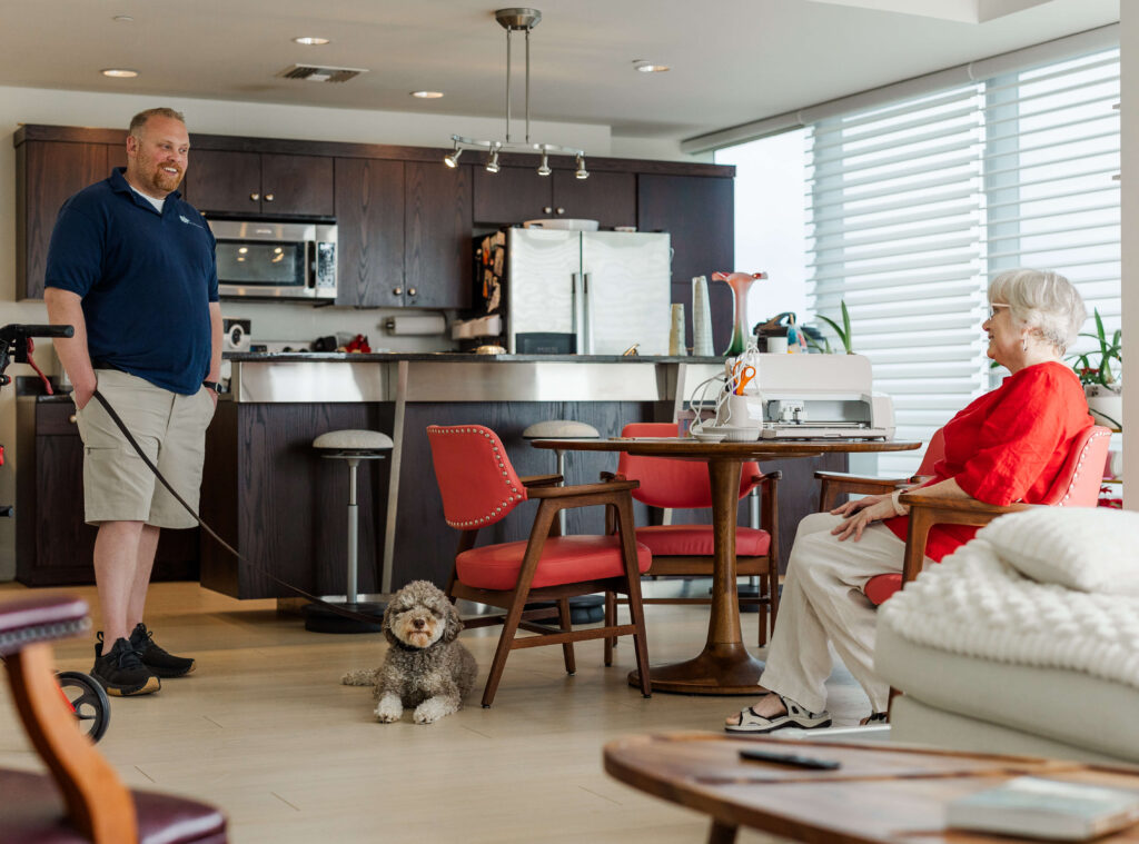 Dogology University trainer providing in-home dog training in Grand Haven MI while a doodle relaxes calmly beside the owner