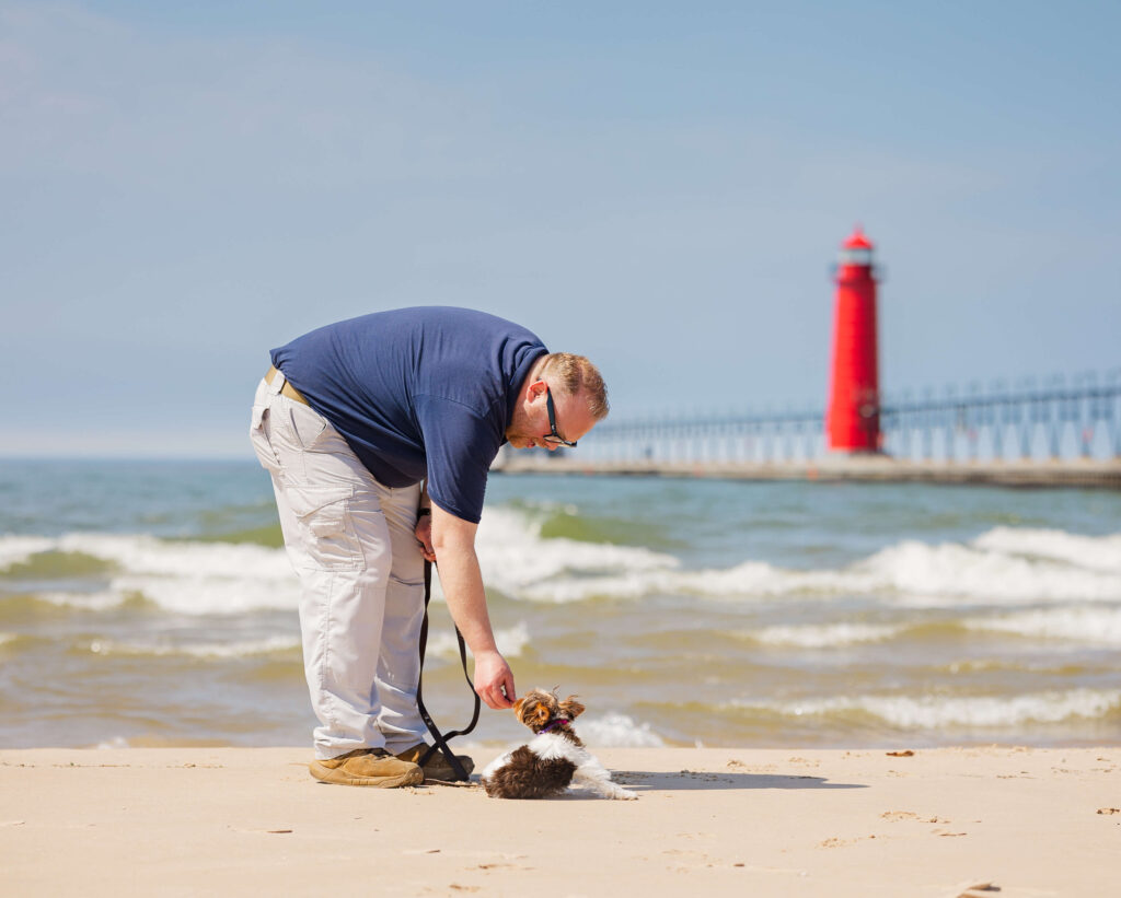 Dog training in Grand Haven MI with a puppy practicing focus near the beach and lighthouse