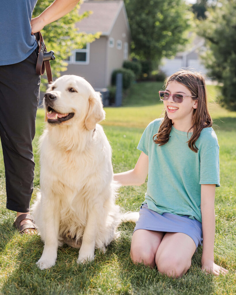 Child sitting beside a trained Golden Retriever during a private dog training lesson in Grand Haven Michigan